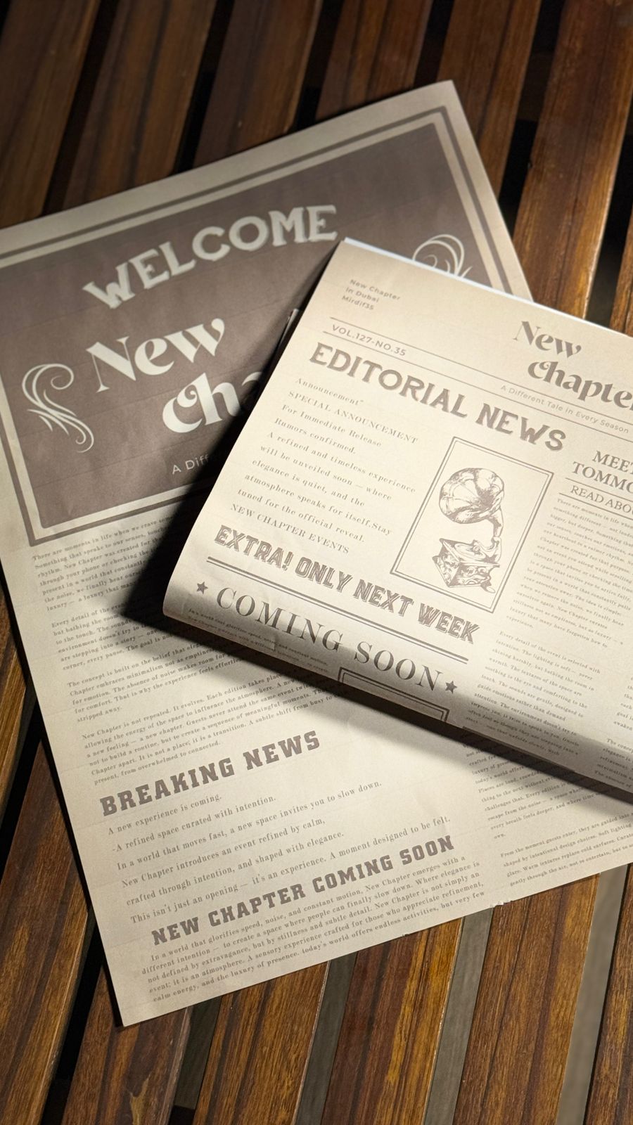 New Chapter welcome newspaper and printed brand materials arranged on a wooden table.