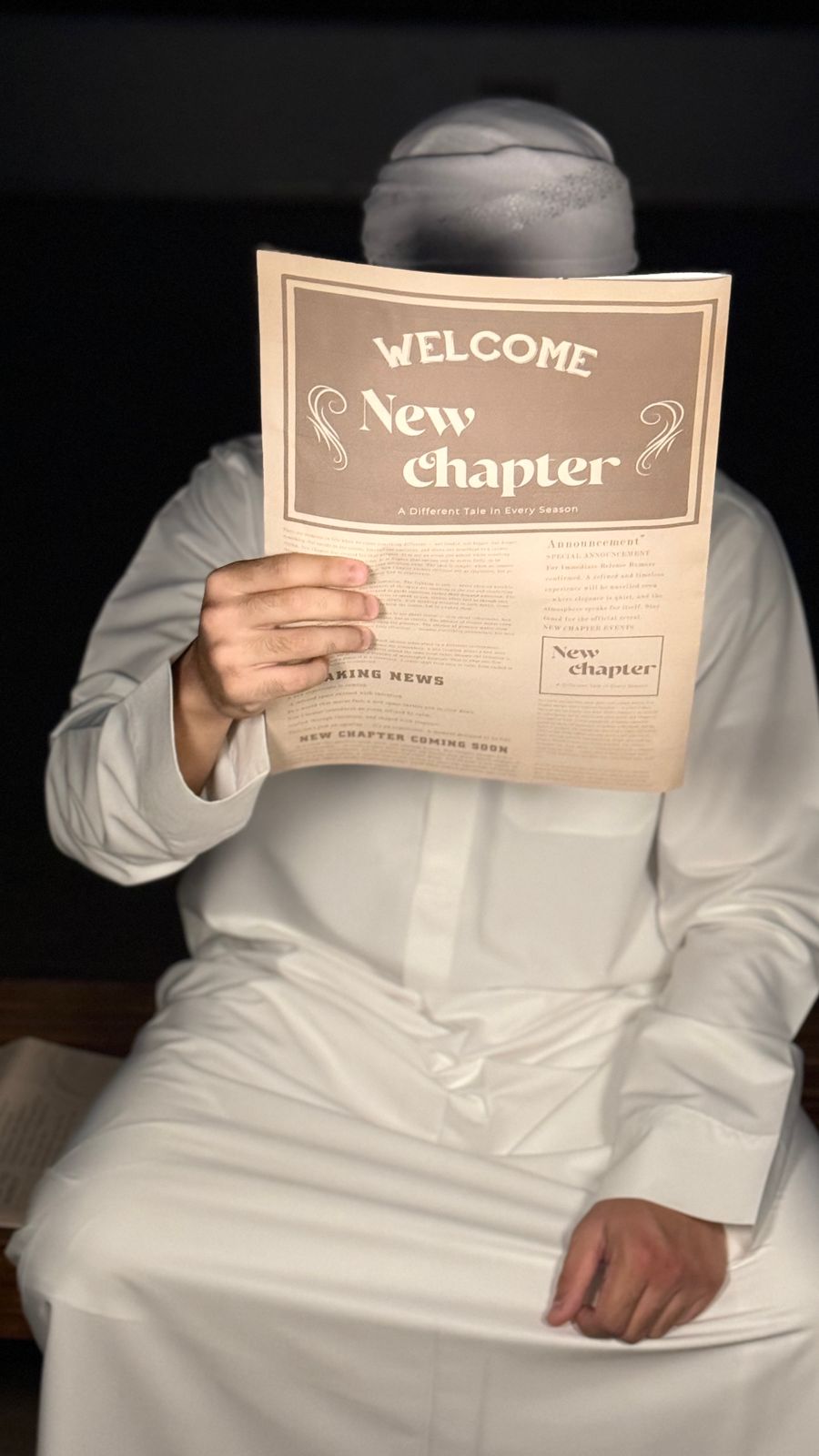 A seated reader holding the New Chapter welcome newspaper.