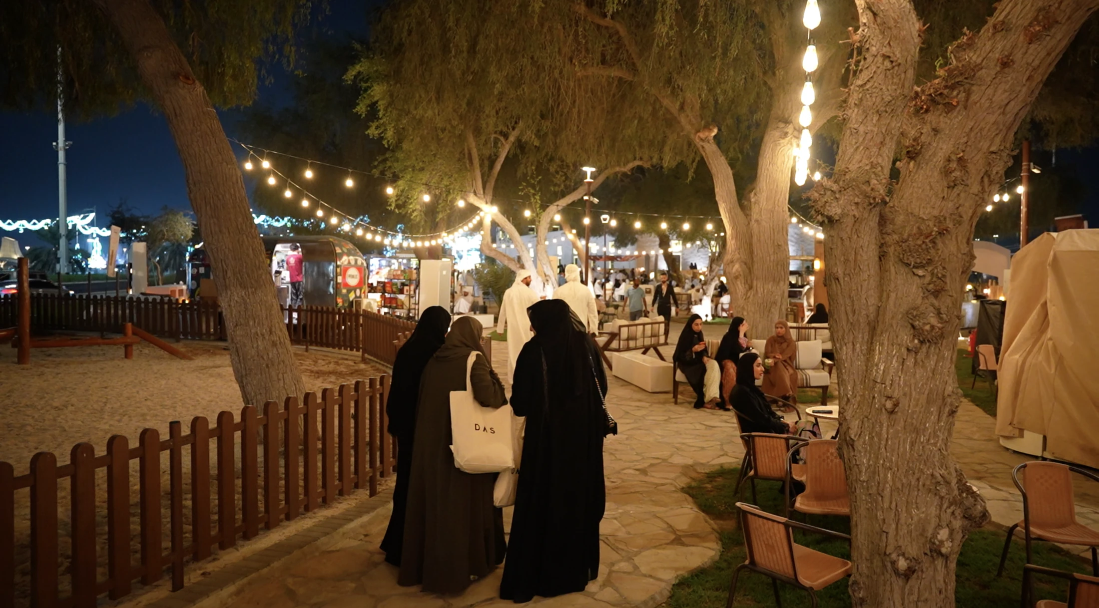 People walking among the event’s illuminated paths, seating and vendors.